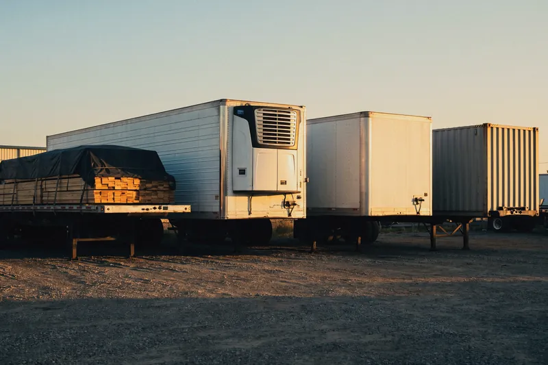 Flatbed, refrigerated, dry van and container trailers parked side by side